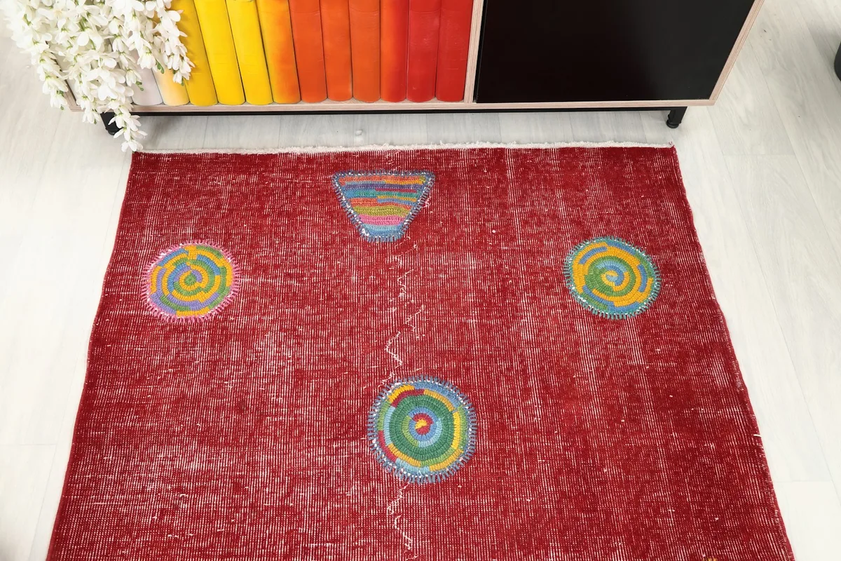 Overhead view of the red rug, capturing its overall layout and the scattered geometric shapes