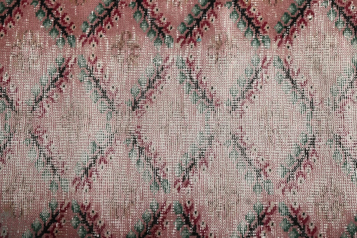 Close-up of the low wool pile, showing the faded rose and cream colors and intricate knotting