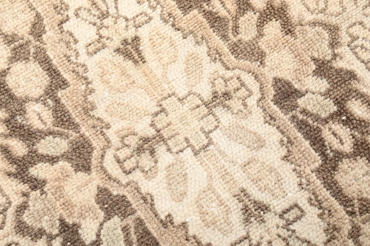 Close-up detail of the hand-knotted pile, showing the texture and variations in the beige and brown wool.
