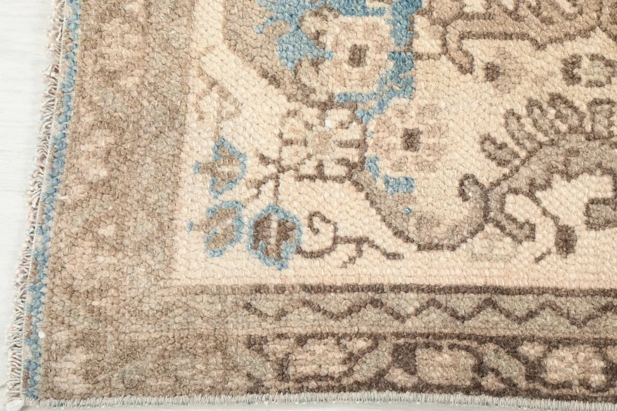 Close-up of a corner of the rug, showing the border design and subtle blue accents in the pattern.