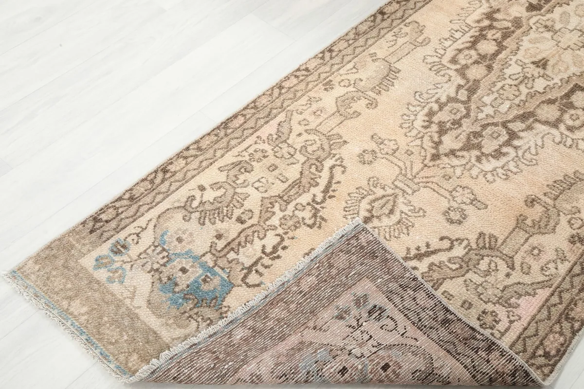 View of the rug folded back, revealing the reverse side and the hand-knotted construction.