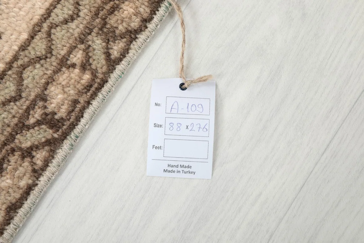Product tag on the rug, indicating it is hand-made in Turkey with size 88 x 276 cm.