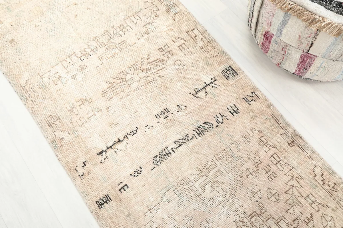 Close-up showing the varied charcoal tribal patterns on the beige field of the rug