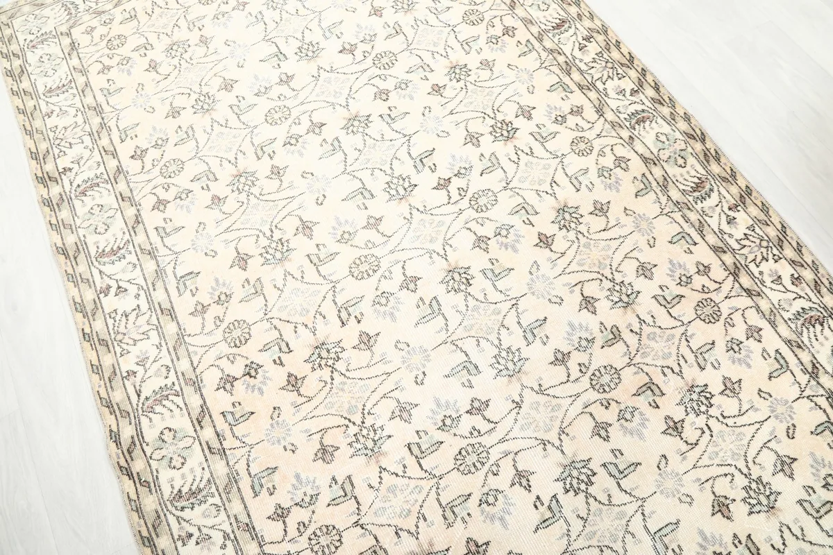 Side angle view highlighting the texture and low pile of the cream vintage rug.