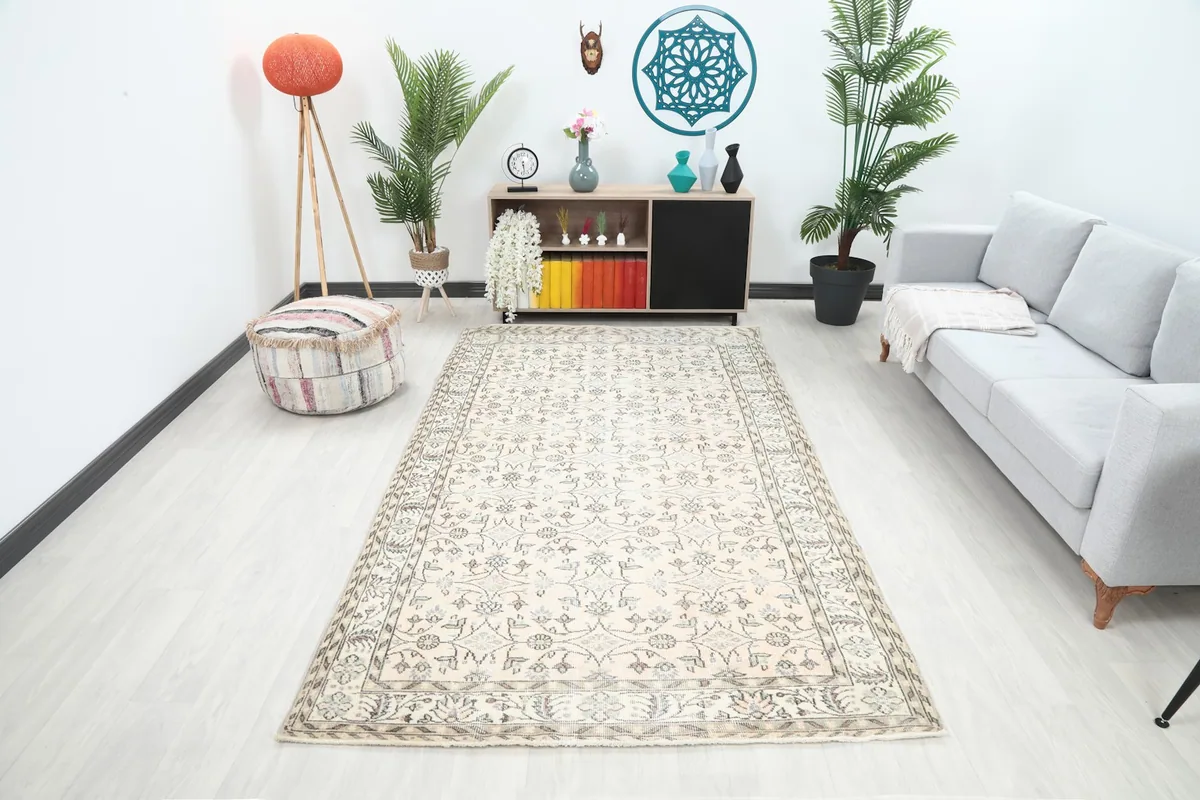 Vintage cream floral rug displayed in a modern living room setting with a light sofa.