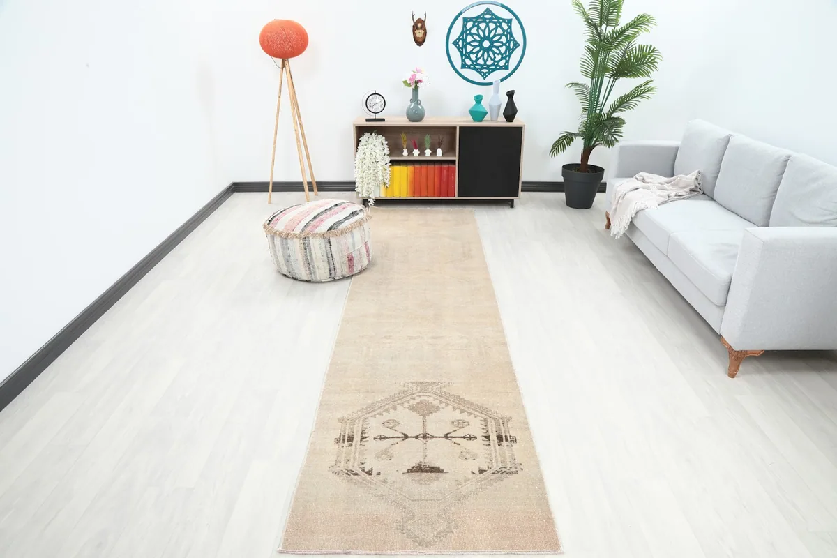 Beige runner rug in a modern living room setting, showcasing its length and color against white flooring.