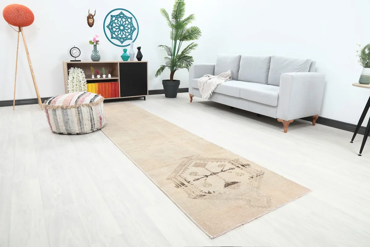 Angled view of the beige runner rug in a living space, highlighting its placement in front of a sofa.