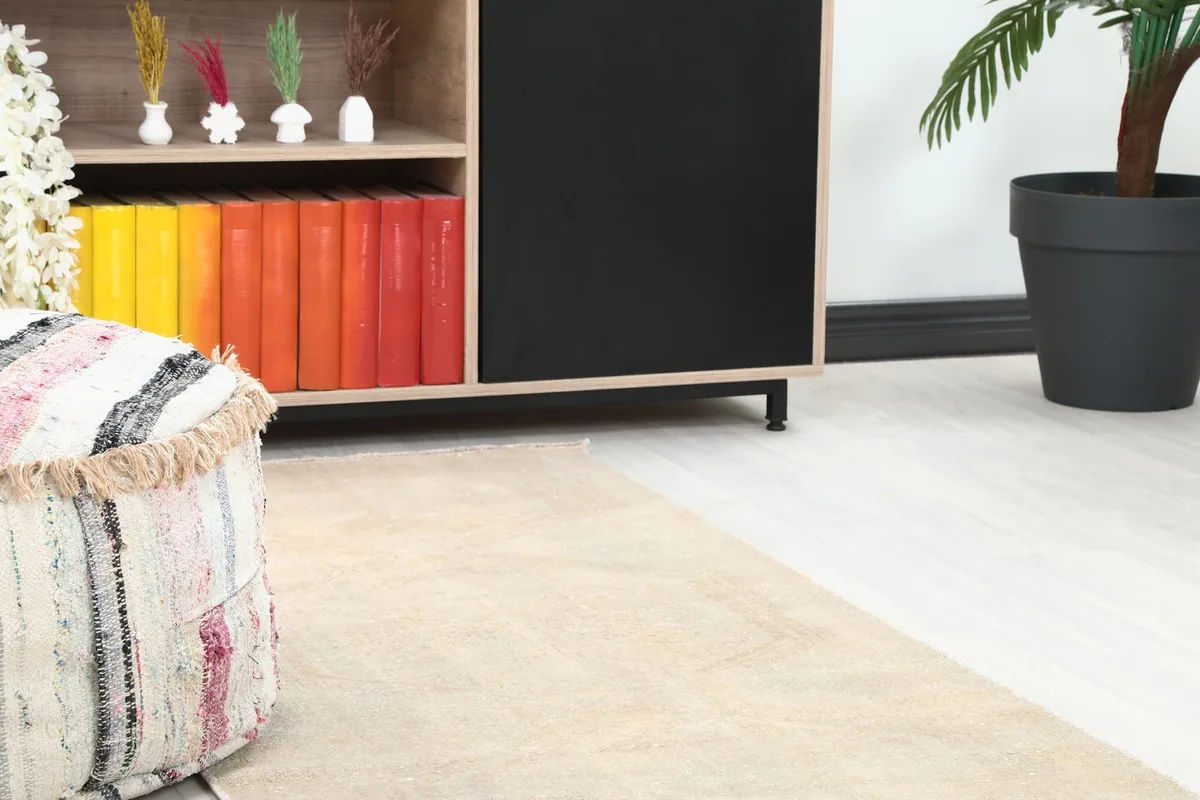 Close-up of the runner rug's texture and color near a decorative pouf and bookshelf.