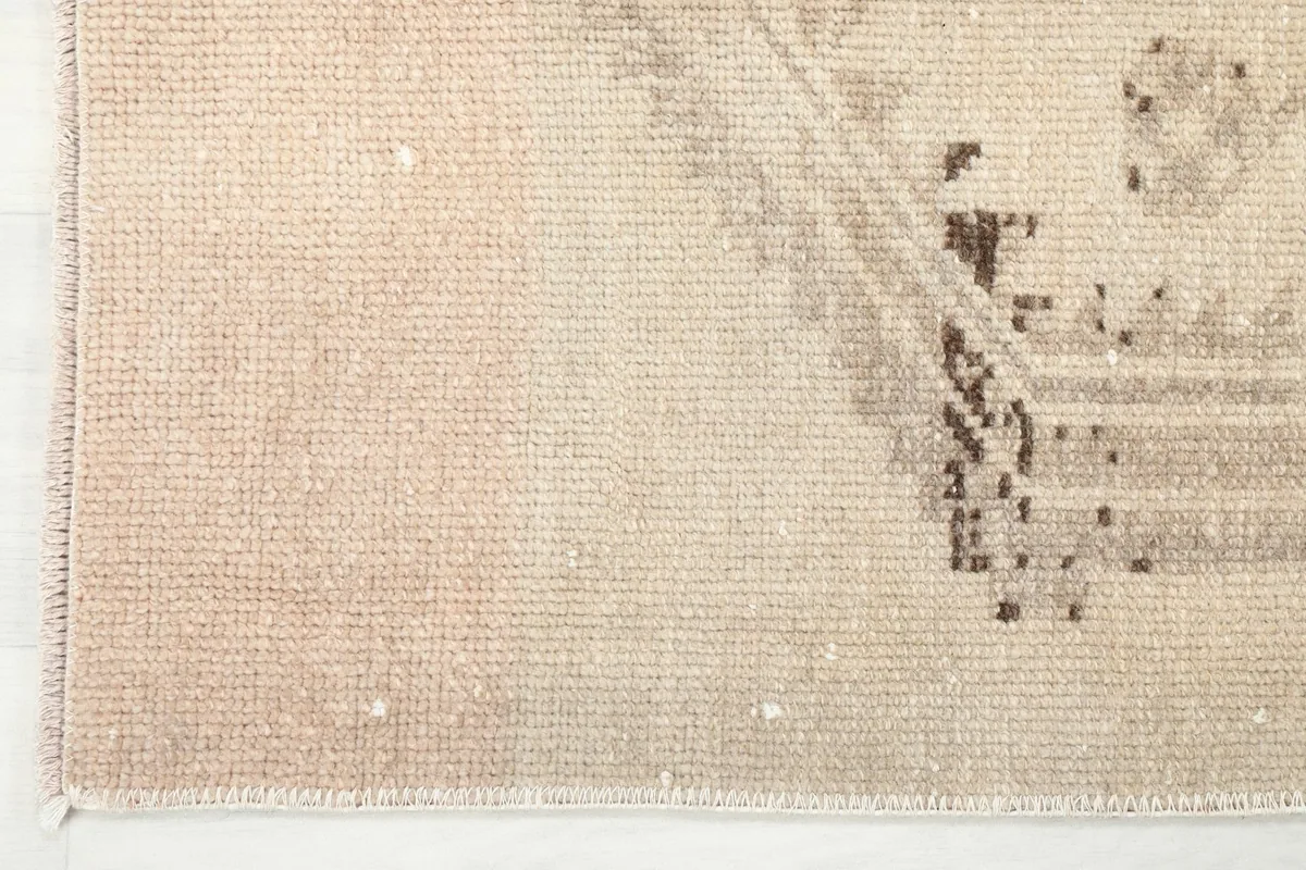 Close-up of one end of the rug, detailing the brown and tan tribal patterns and fringe.
