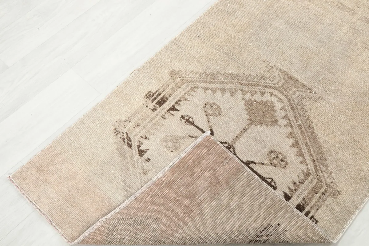Corner of the rug folded back, showing the wool pile on cotton foundation and the reverse side.