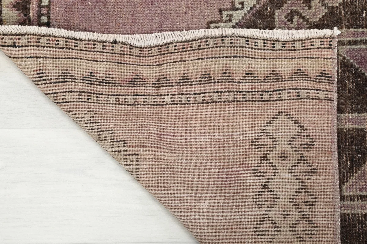 Close-up of the rug's cotton foundation and hand-knotted construction from the back