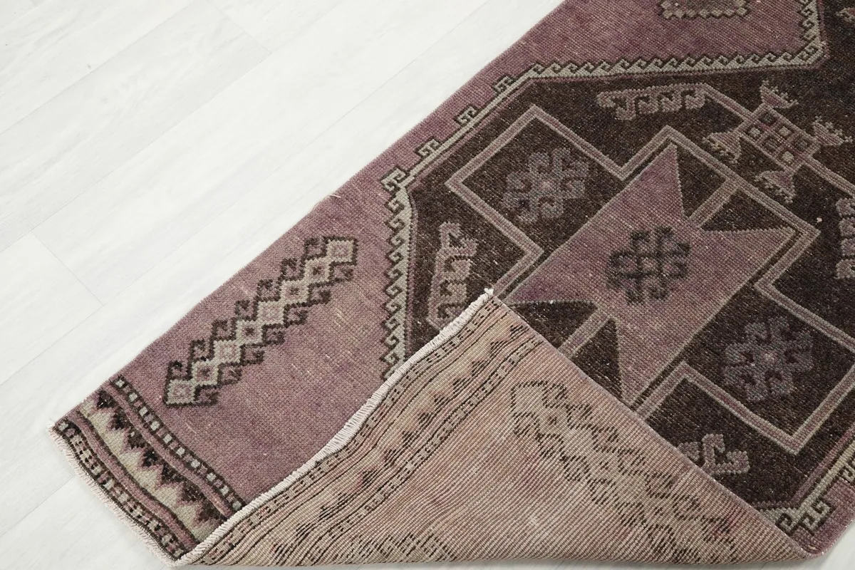 Corner of the runner rug folded to reveal the backside and knotting