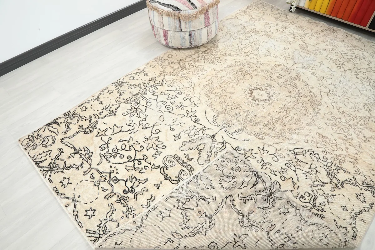 View of the ivory and charcoal rug with a corner folded back, showing the back and front texture