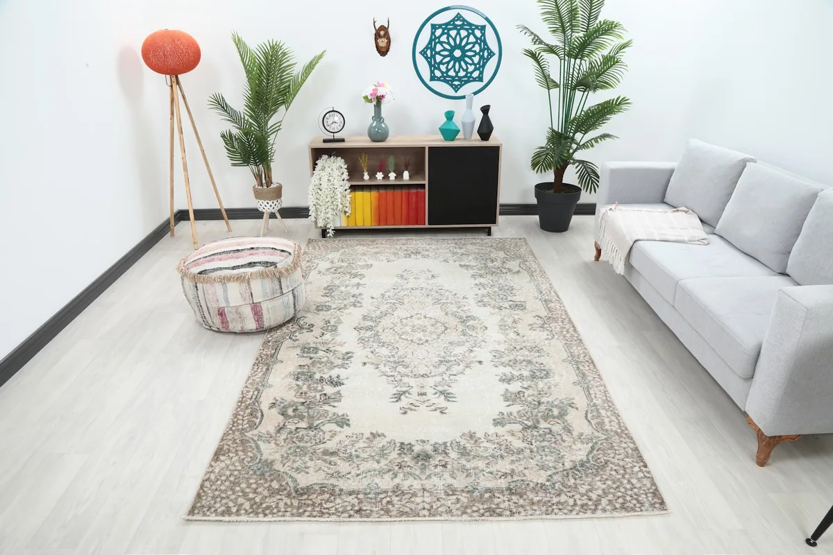 Ivory vintage rug placed in a living room setting with a gray sofa and wooden furniture