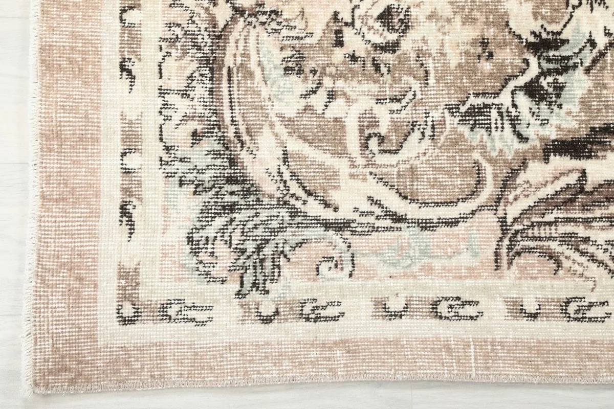 Corner detail of the rug's border, displaying the beige and charcoal patterns and fringe.