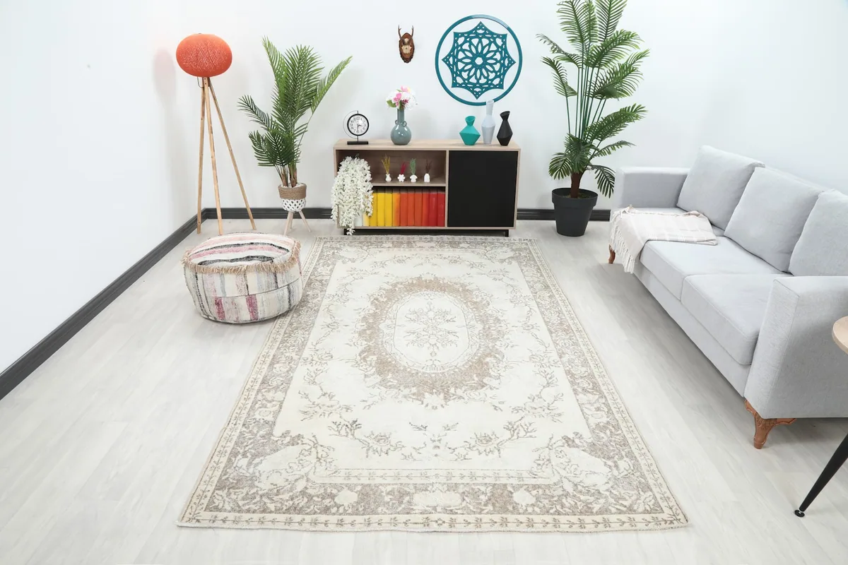 Vintage ivory and beige rug displayed in a bright living room setting with a light gray sofa