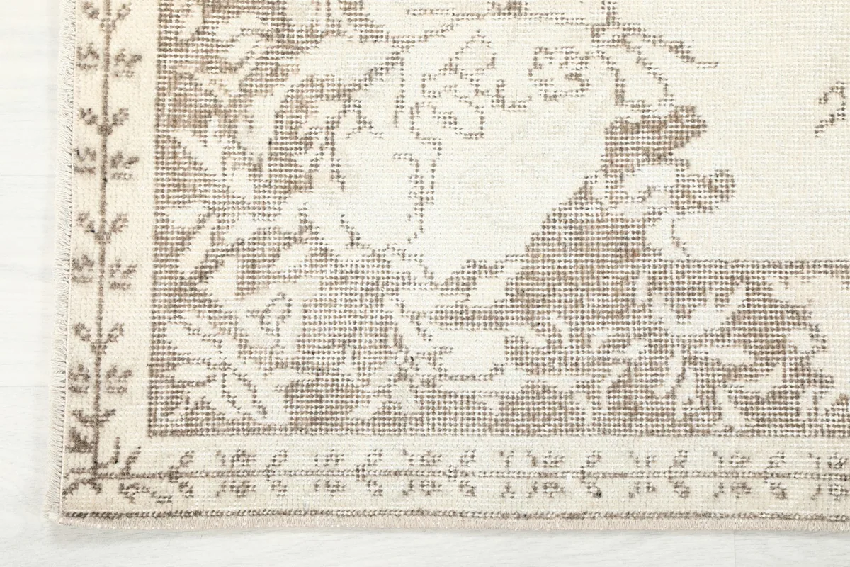 Corner detail of the rug showing the delicate floral border design and fringe