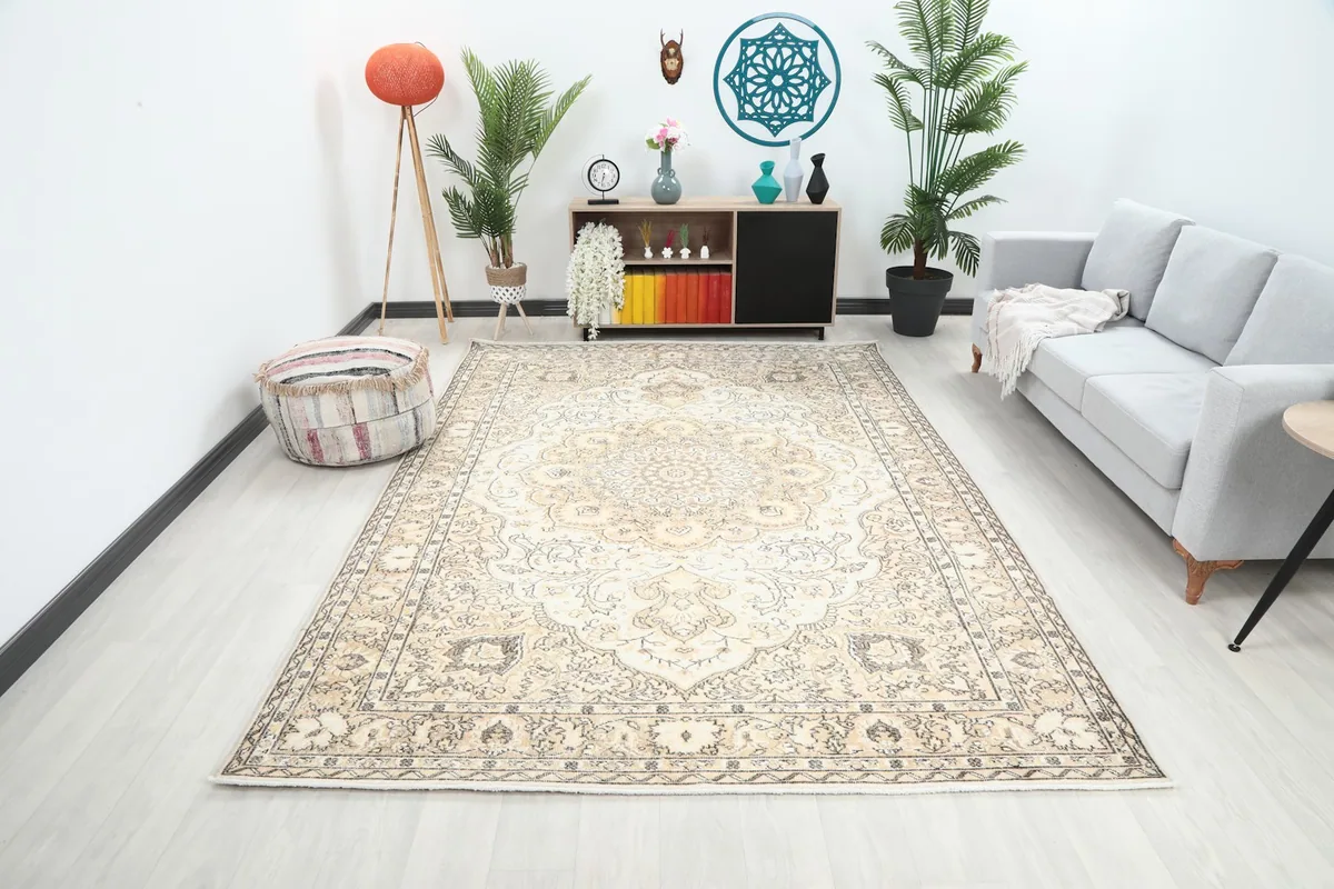 Large ivory and tan vintage rug displayed in a modern living room setting with a light gray sofa.