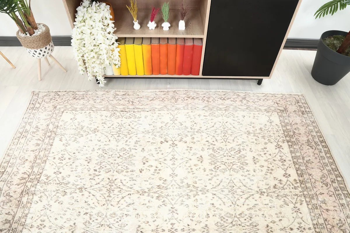 Overhead view of the ivory floral rug in a room with a colorful bookshelf