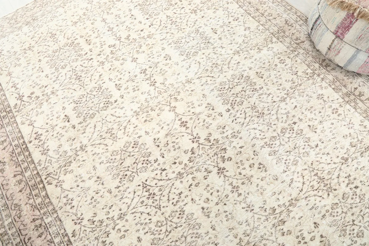 Detailed view of the ivory field and subtle rose floral motifs on the vintage rug