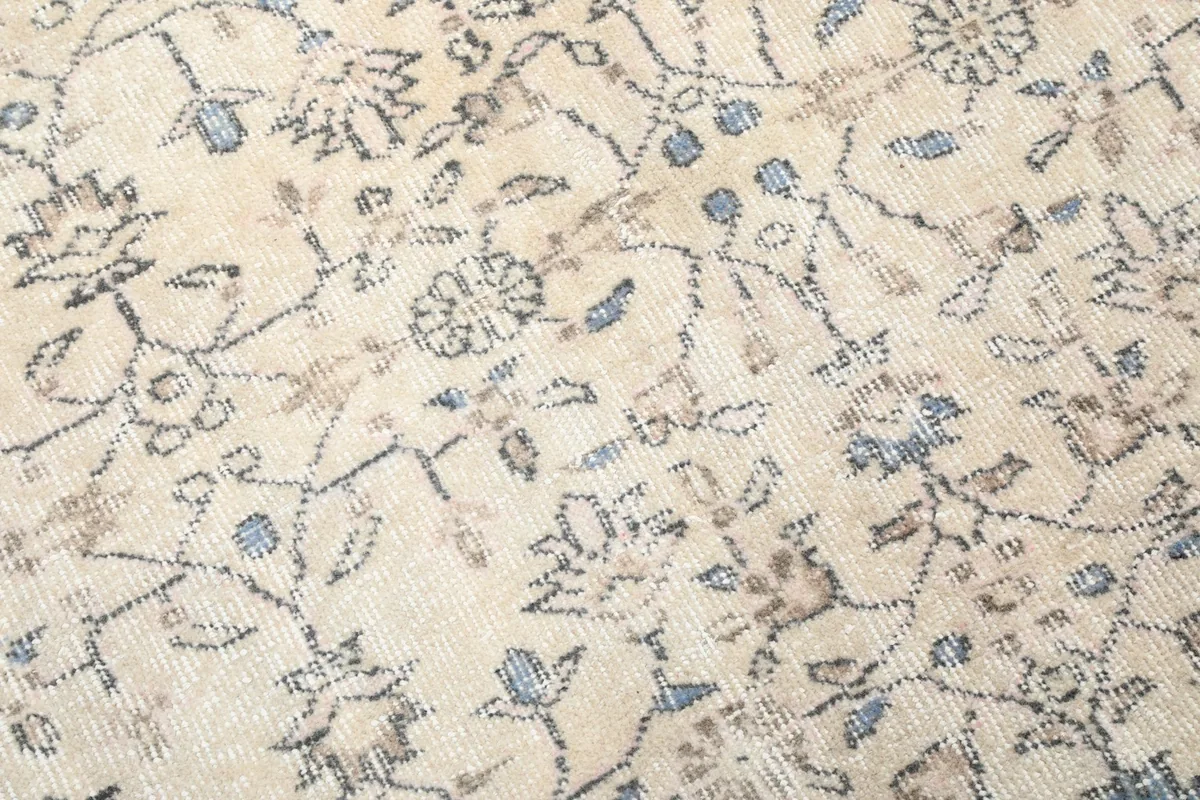 Close-up detail of the hand-knotted wool pile and faded floral motifs in blue and beige