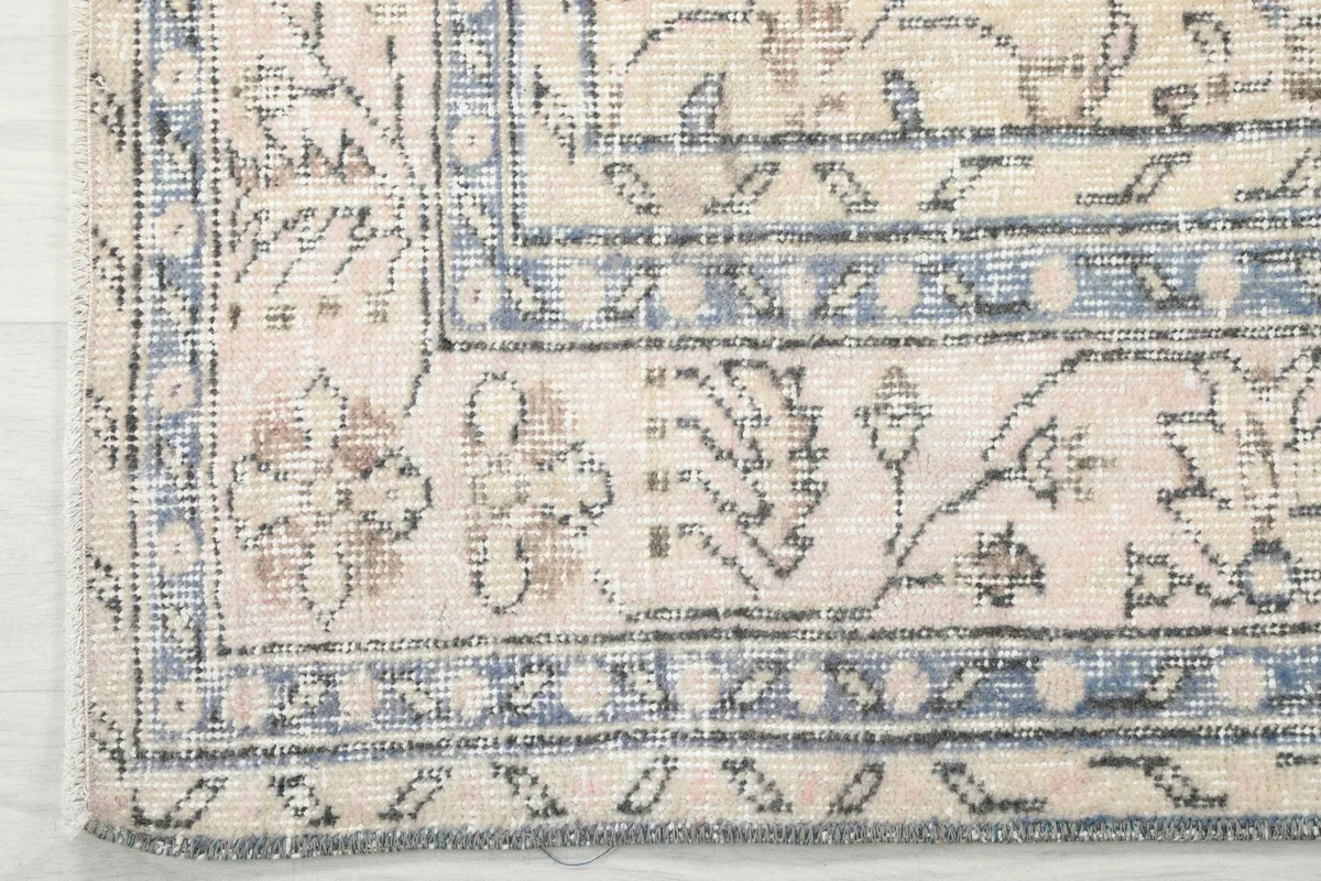 Corner detail showing the intricate blue geometric border and ivory field patterns