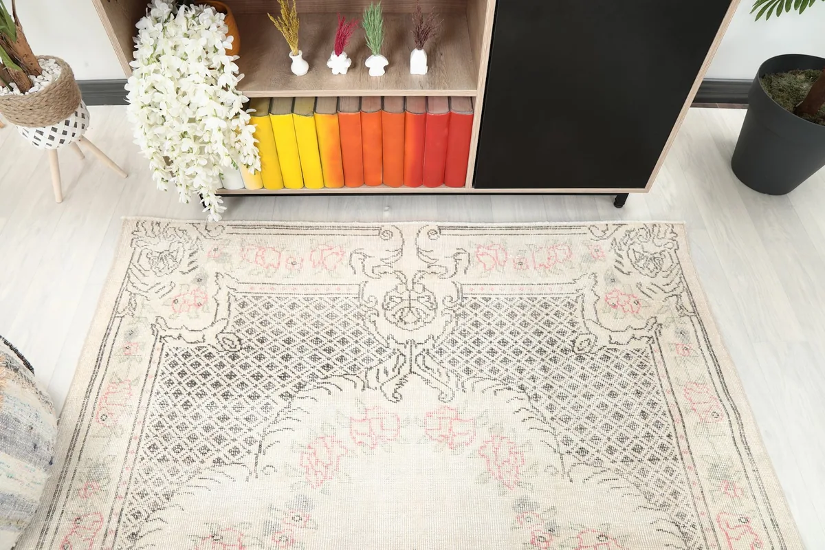Detail of the rug's top section and border, seen from an angle with furniture in the background