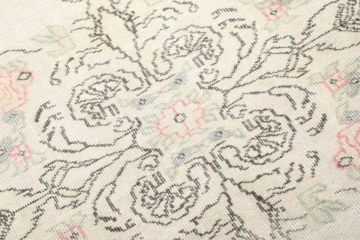 Detailed view of the rug's faded rose and gray motifs, showing the hand-knotted texture
