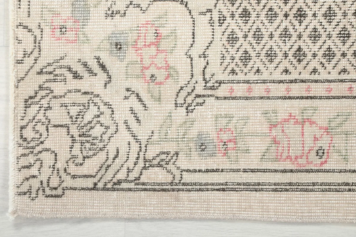 Corner detail of the rug's border, showcasing the geometric and floral patterns and fringe
