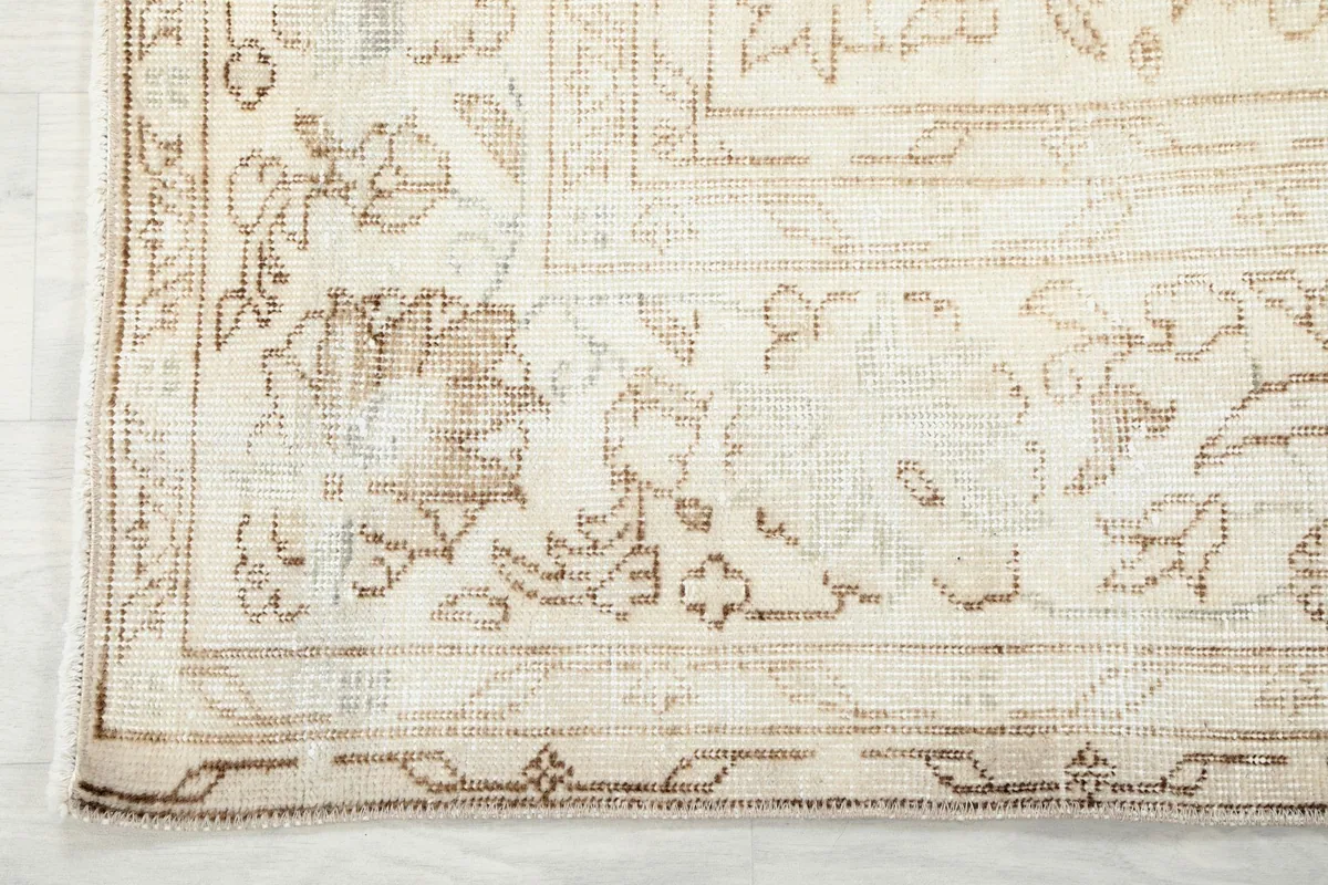 Detailed shot of the rug's border and corner, showing the hand-knotted texture and wear