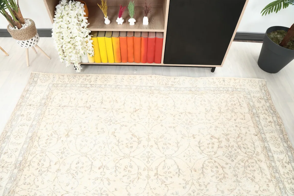 Top-down angle of the ivory rug's faded floral design, showing its placement near a bookshelf.