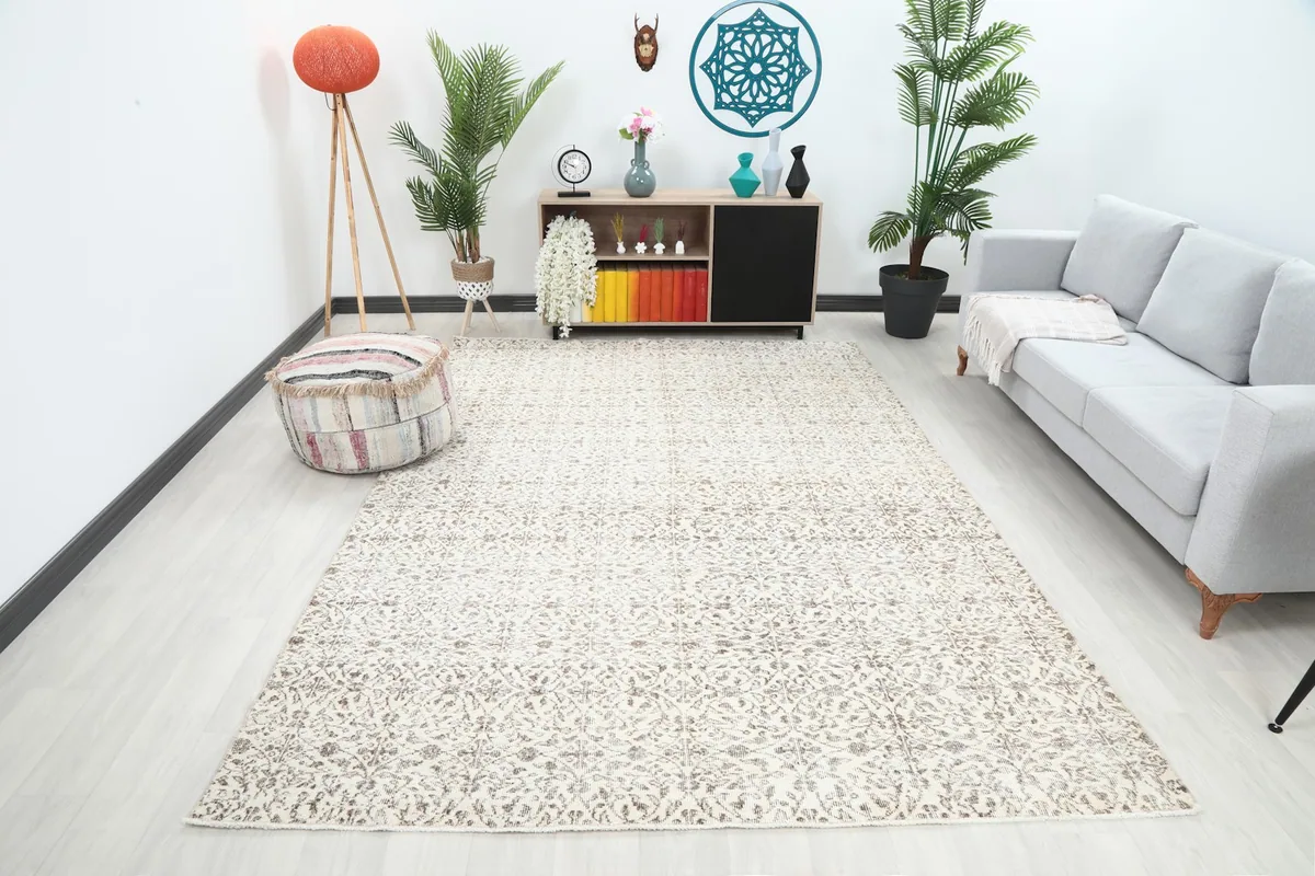 Ivory and brown vintage area rug placed in a modern living room setting with a sofa and ottoman