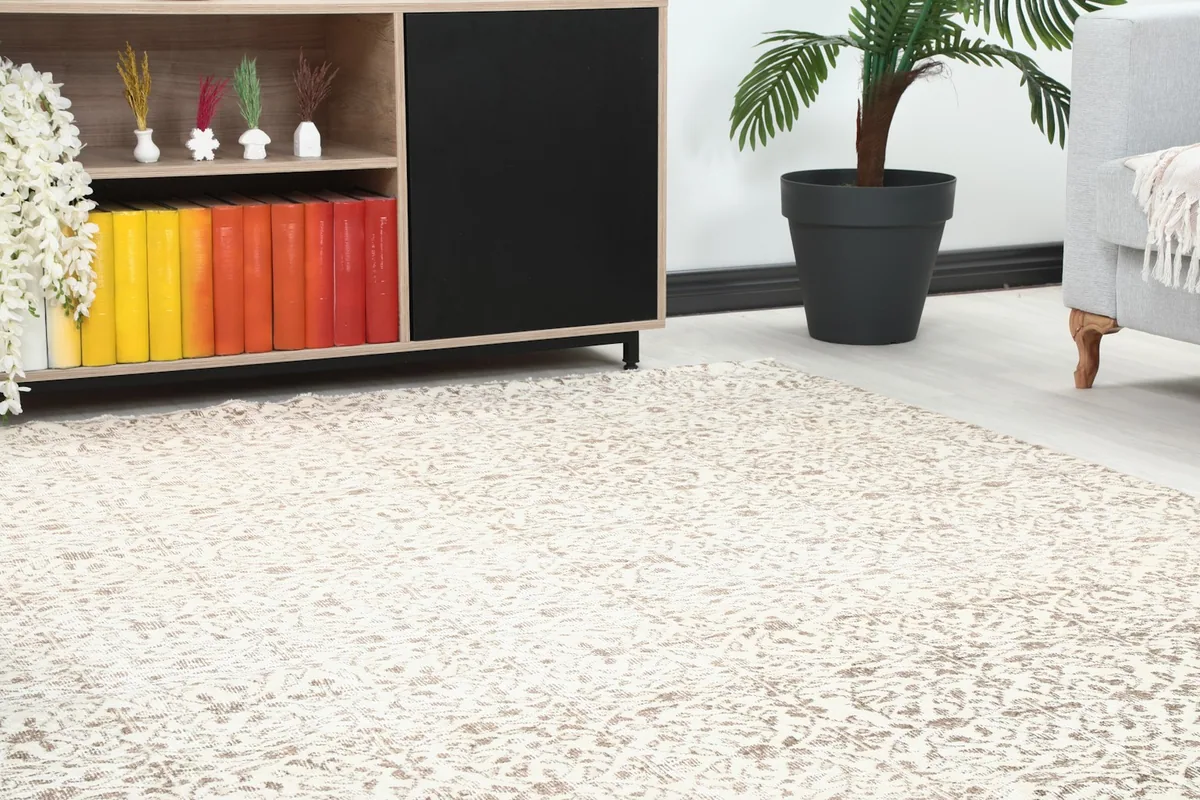 Close-up view of the rug's pattern on the floor next to a wooden cabinet with colorful books