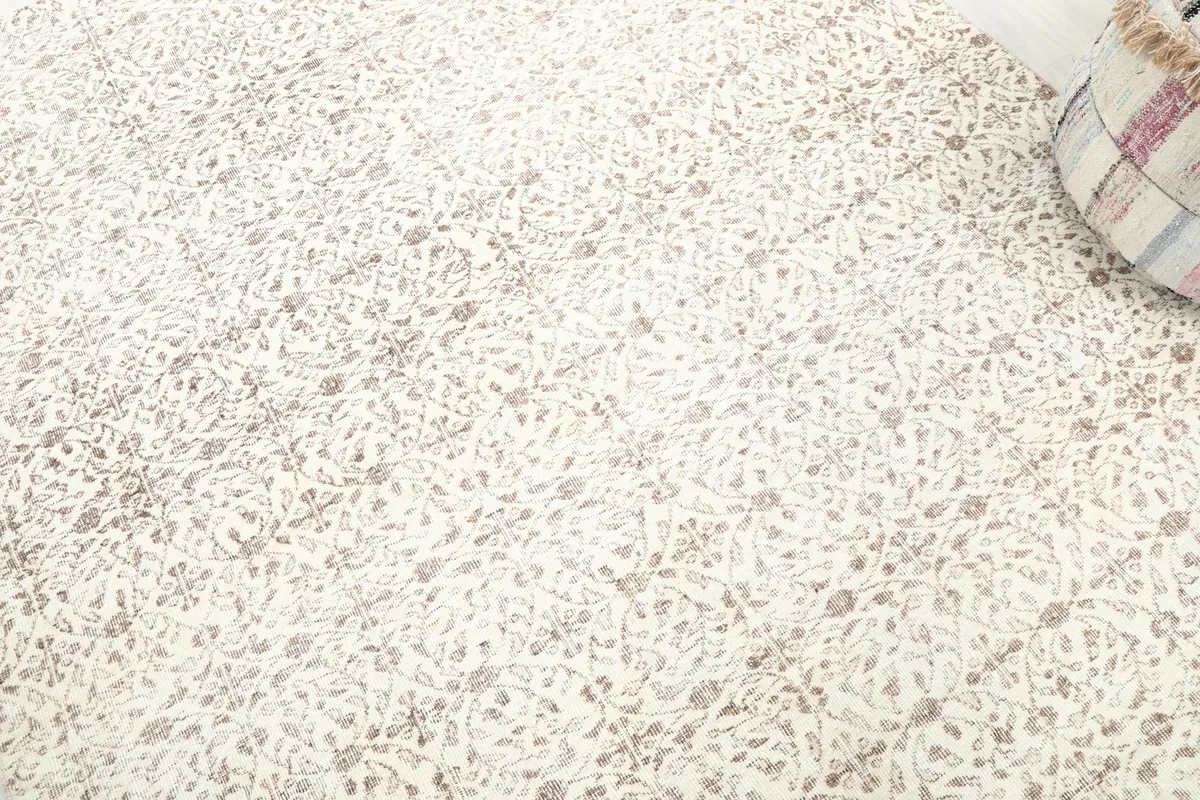 Detailed close-up of the ivory field and the faded brown floral and geometric motifs on the rug