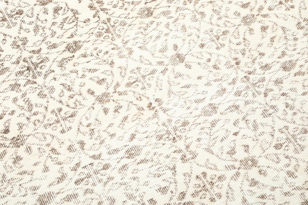 Macro view highlighting the distressed wool pile and intricate pattern details of the vintage rug