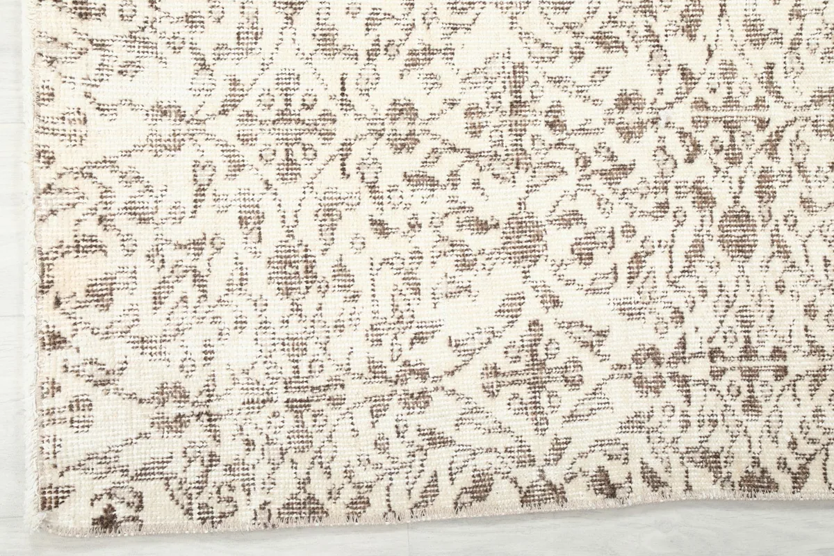 Corner detail of the hand-knotted rug, showing the blend of ivory and brown colors