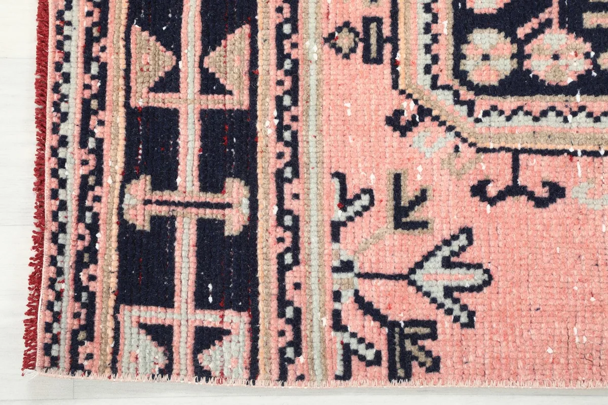 Detailed view of the navy and beige border design next to the rose field of the runner