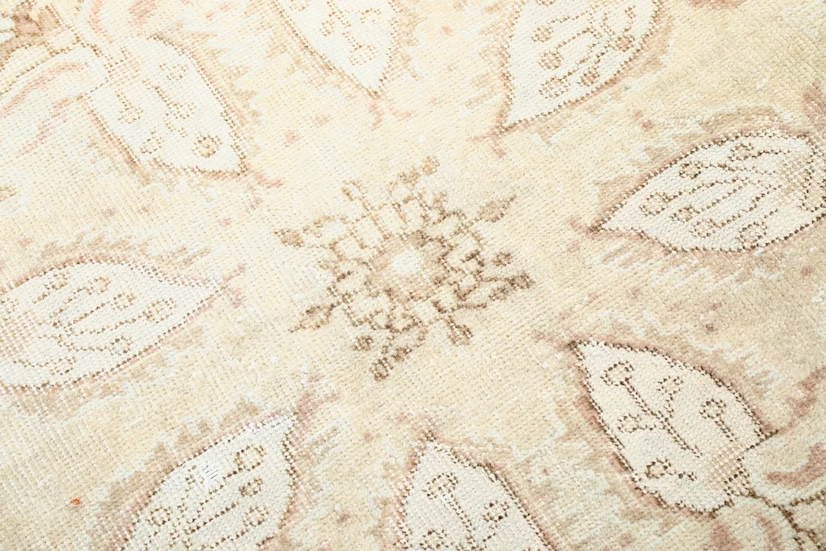 Close-up texture of the cream wool pile and the intricate rose and beige floral patterns