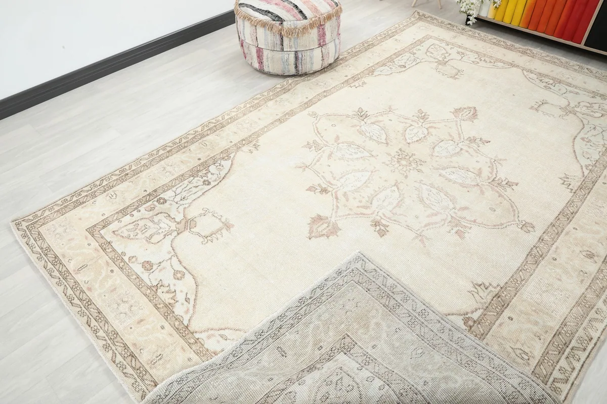 Corner of the cream rug folded back slightly, showing the reverse side and overall design