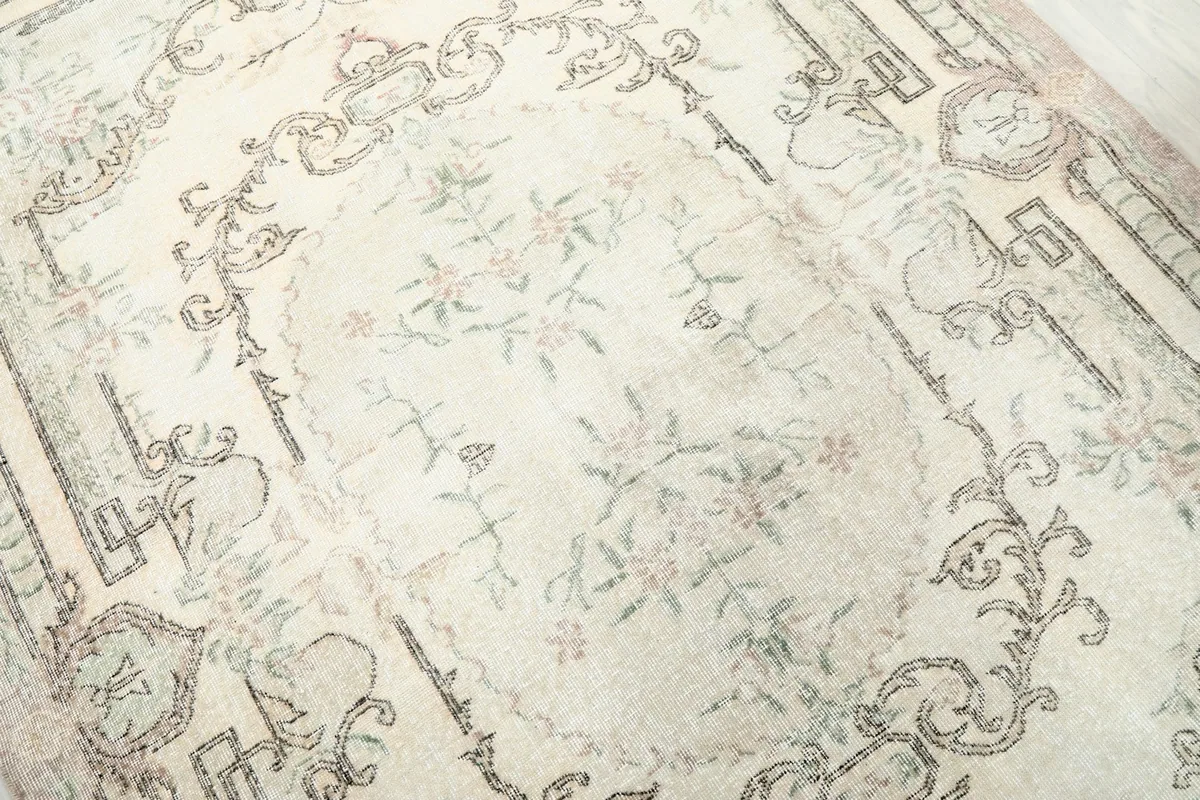 Detailed view of the intricate botanical medallion and subtle color variations within the ivory field.