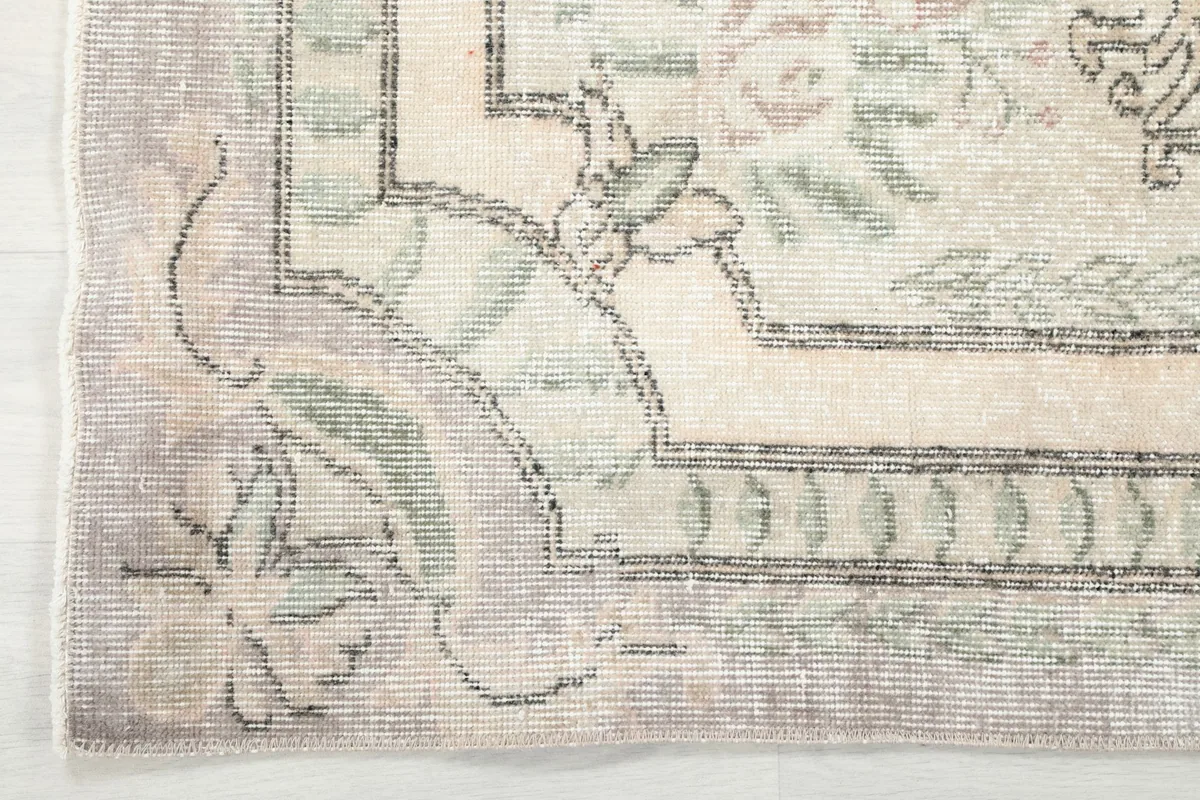 Corner detail showing the patterned gray border and the transition to the ivory field.
