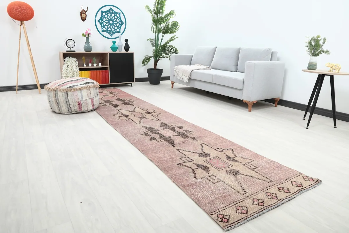 Angled view of the rose and beige geometric runner rug in a living space, showcasing its design.
