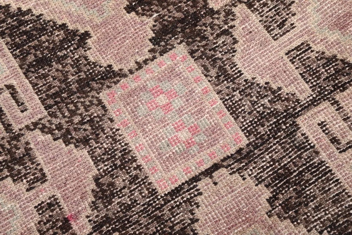 Close-up view of the low wool pile, showing the texture and color variations in the rose and beige areas.