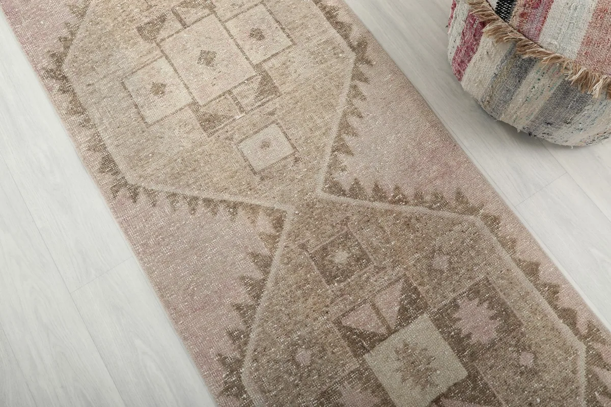 Close-up of the hand-knotted wool pile and geometric motifs in rose and tan