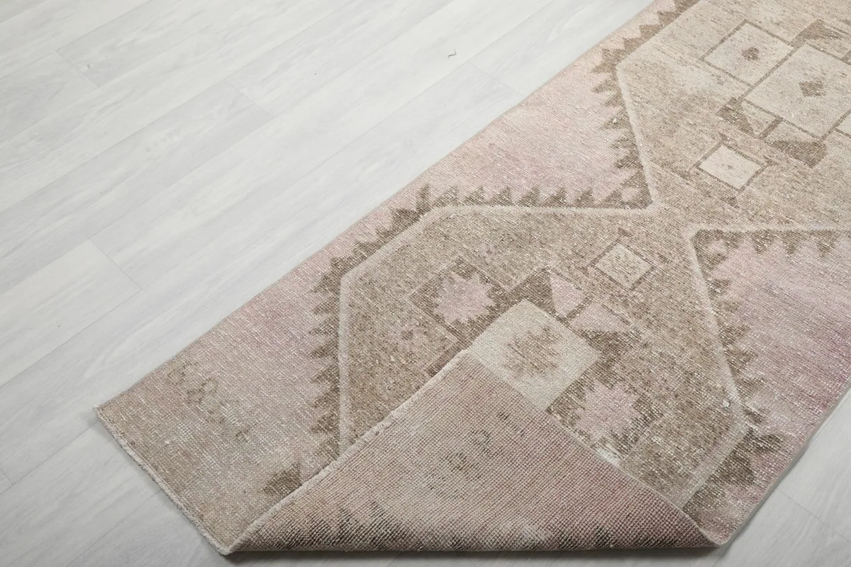 Corner of the runner rug folded to reveal the foundation and a glimpse of the back