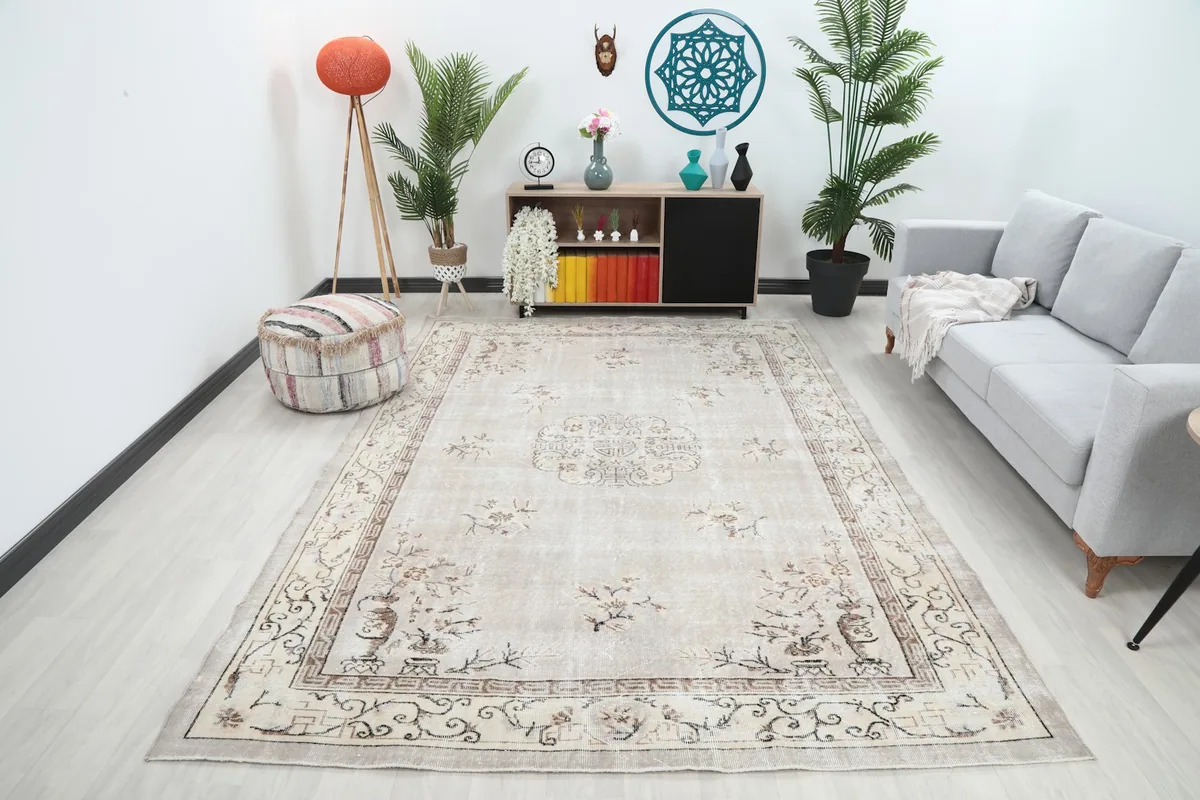 Beige vintage rug displayed in a modern living room setting with a gray sofa and plants