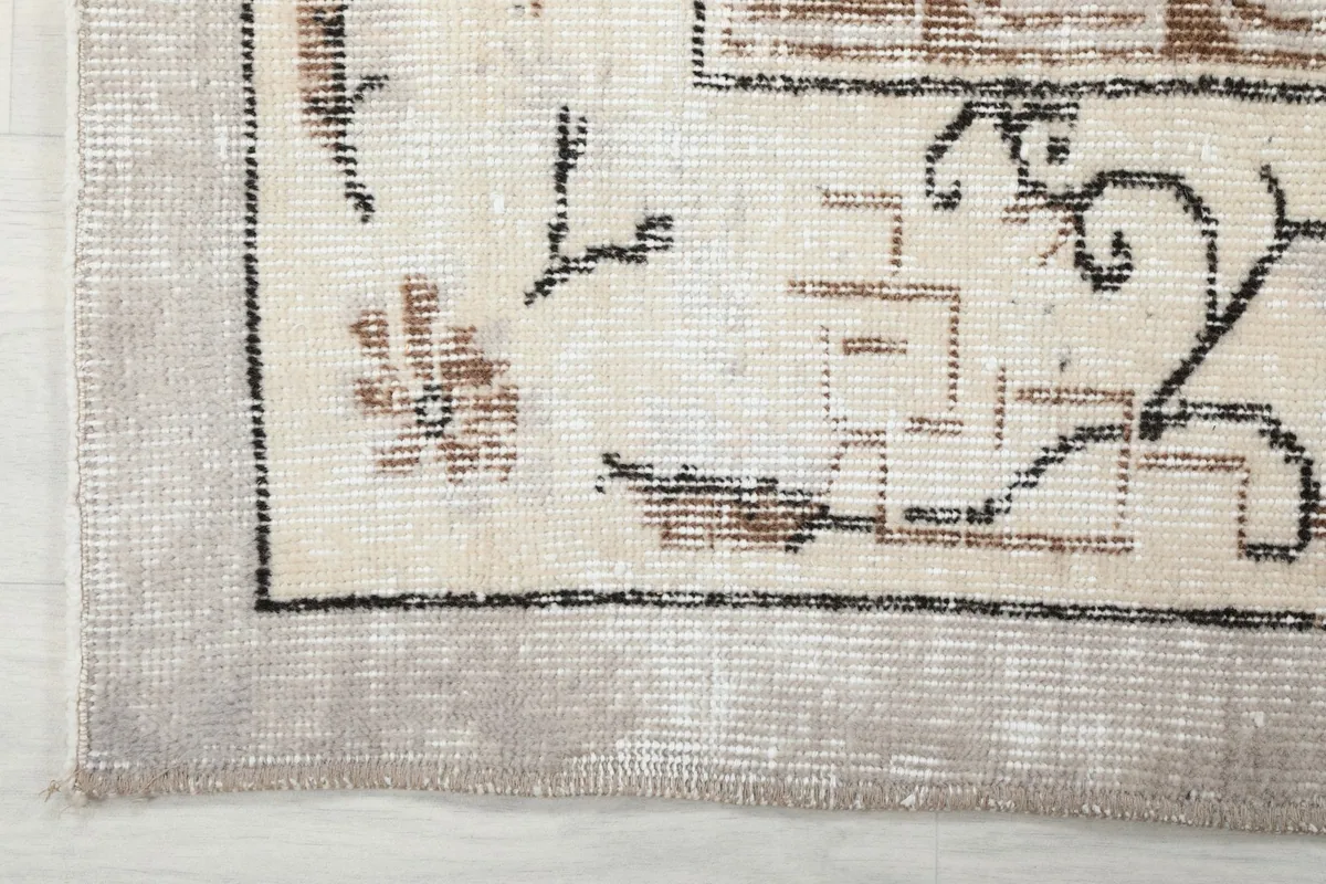 Corner detail of the rug's border, showcasing the geometric and floral elements and fringe