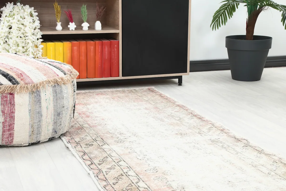 Close-up view of the runner rug next to a striped ottoman and wooden shelf