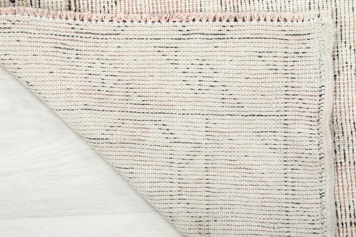 Close-up of the back of the hand-knotted wool rug, showing the cotton foundation