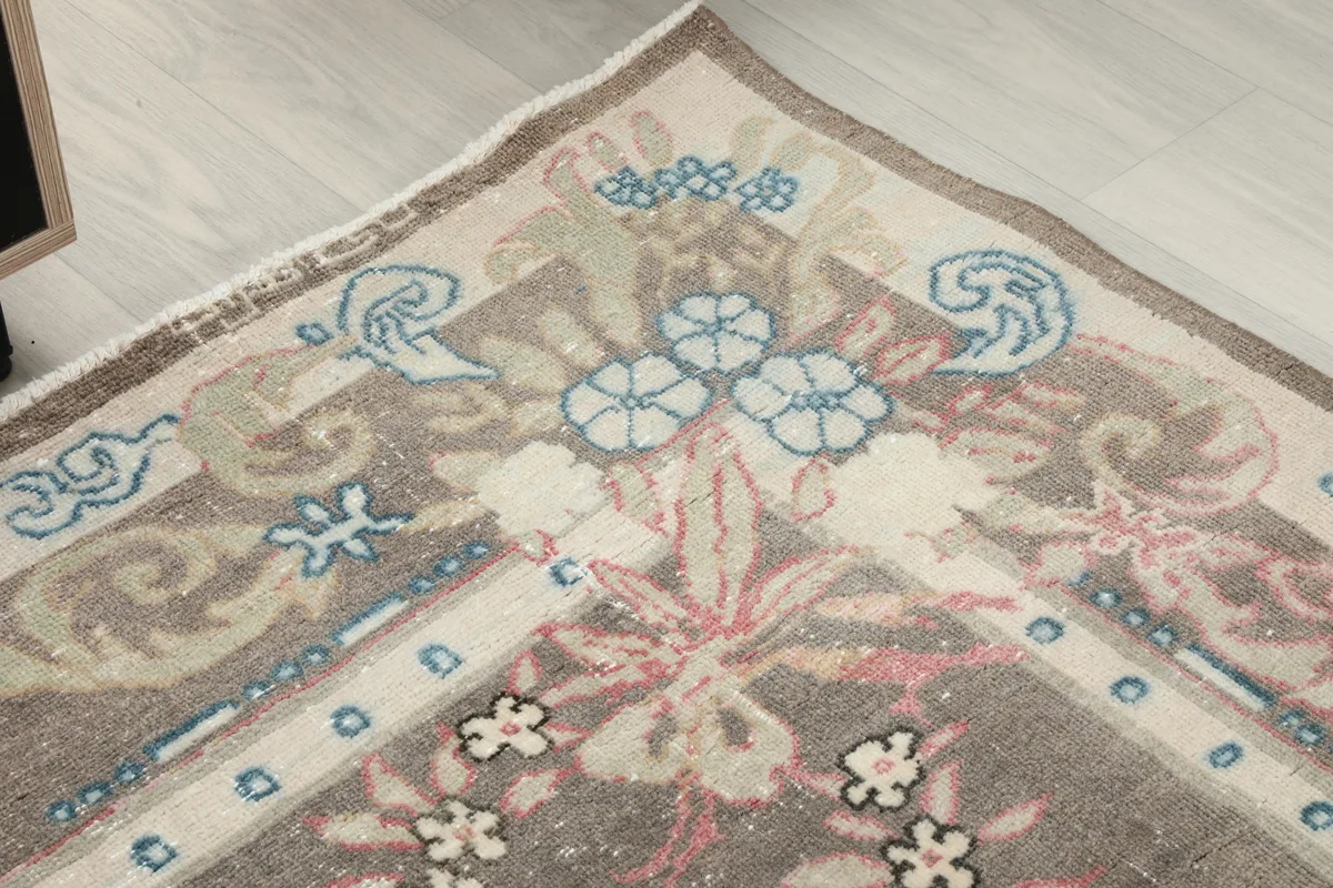 Corner detail of the Gray Rose Medallion Anatolian Rug, showing the blend of blue, beige, and rose in the border.